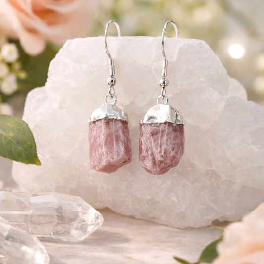 Pink stone earrings on a white rock with flowers in the background